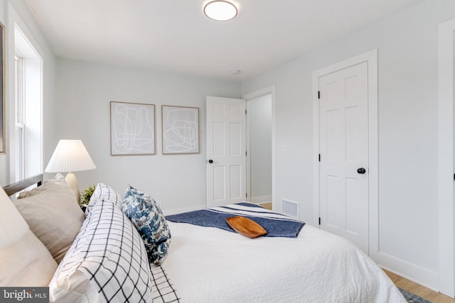 bedroom with multiple windows and hardwood / wood-style flooring