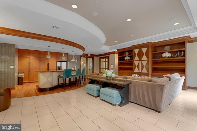 living room featuring crown molding, a tray ceiling, and light wood-type flooring