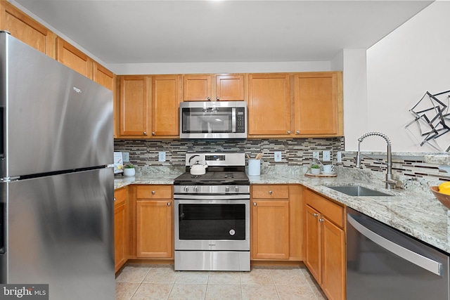 kitchen with sink, backsplash, light stone countertops, and appliances with stainless steel finishes