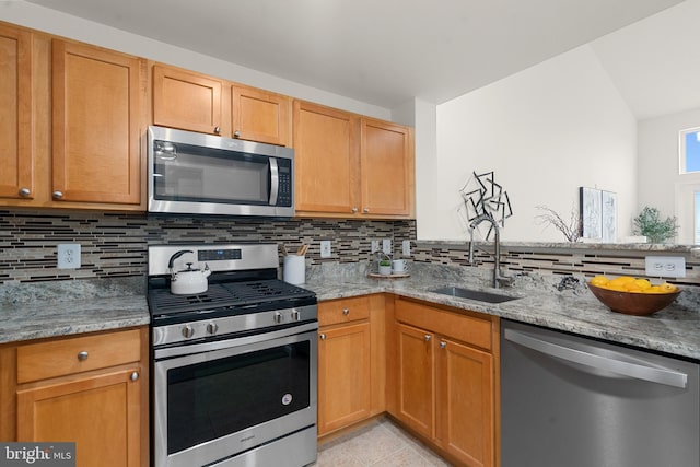 kitchen featuring appliances with stainless steel finishes, sink, and light stone counters