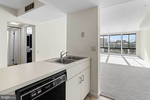 kitchen featuring sink, a wall of windows, dishwasher, light colored carpet, and white cabinets