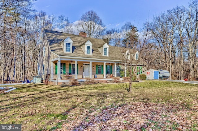 cape cod house featuring a shed, a front yard, and a porch