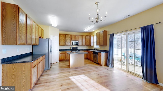 kitchen with appliances with stainless steel finishes, a center island, sink, and light wood-type flooring