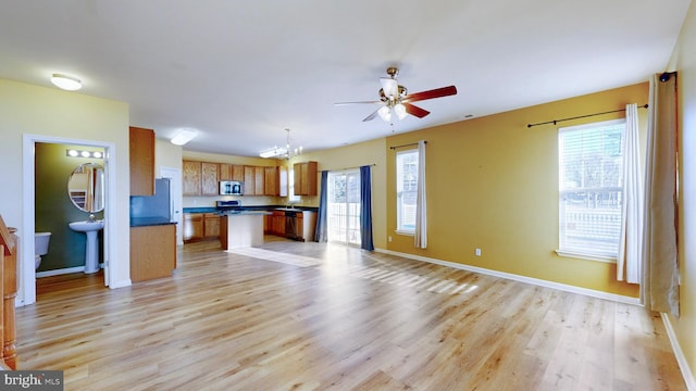 kitchen with refrigerator, ceiling fan with notable chandelier, hanging light fixtures, and light wood-type flooring