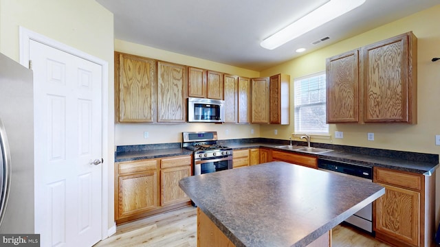 kitchen with sink, a kitchen island, light hardwood / wood-style floors, and appliances with stainless steel finishes