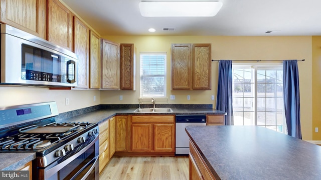 kitchen with appliances with stainless steel finishes, light hardwood / wood-style floors, sink, and a wealth of natural light