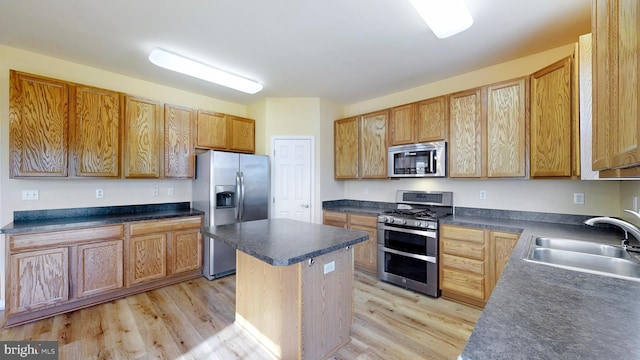 kitchen with stainless steel appliances, a kitchen island, sink, and light hardwood / wood-style floors