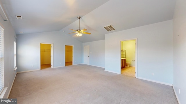 interior space featuring ensuite bathroom, lofted ceiling, a spacious closet, ceiling fan, and light carpet