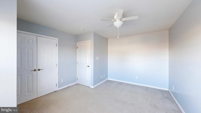 unfurnished bedroom with ceiling fan, light colored carpet, and a closet