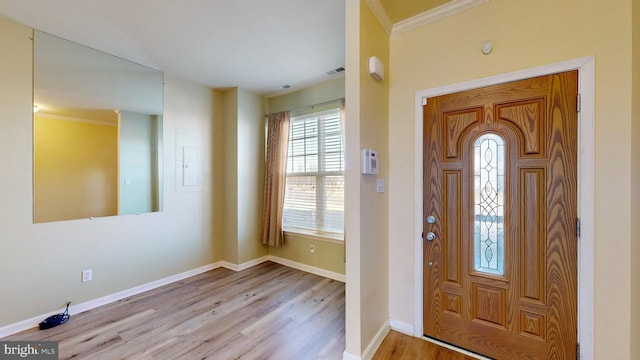 entryway with ornamental molding and light hardwood / wood-style floors