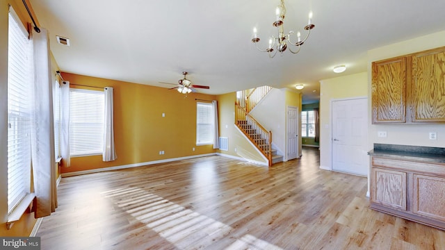 unfurnished living room with ceiling fan with notable chandelier and light wood-type flooring