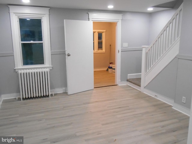 empty room with radiator heating unit and light hardwood / wood-style flooring