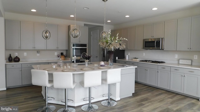 kitchen featuring stainless steel appliances, gray cabinets, and a center island with sink