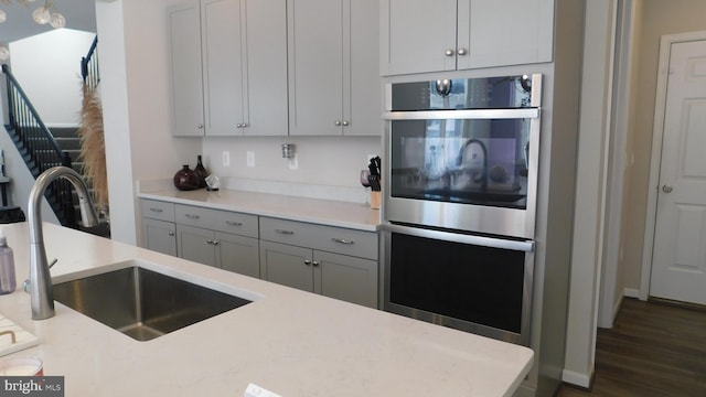 kitchen with sink, stainless steel double oven, and dark hardwood / wood-style floors