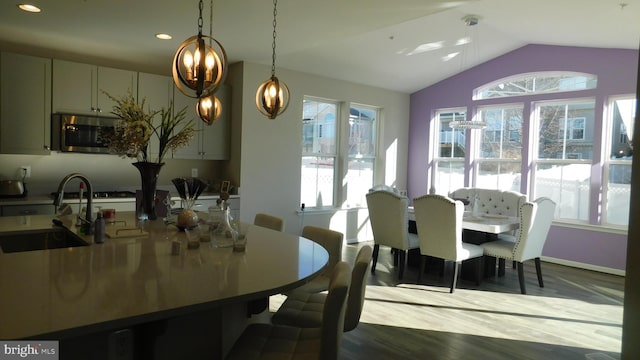 dining space with lofted ceiling, wood-type flooring, and sink