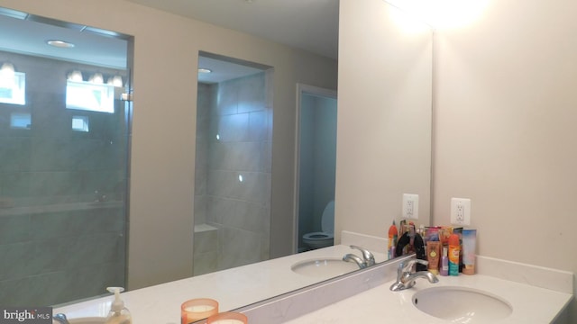 bathroom featuring vanity, a tile shower, and toilet