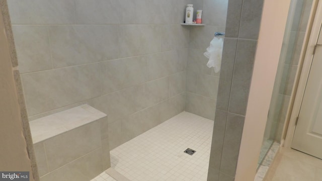 bathroom with a tile shower and tile patterned flooring