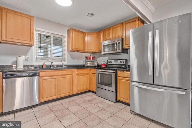 kitchen featuring dark stone countertops, sink, light tile patterned floors, and stainless steel appliances