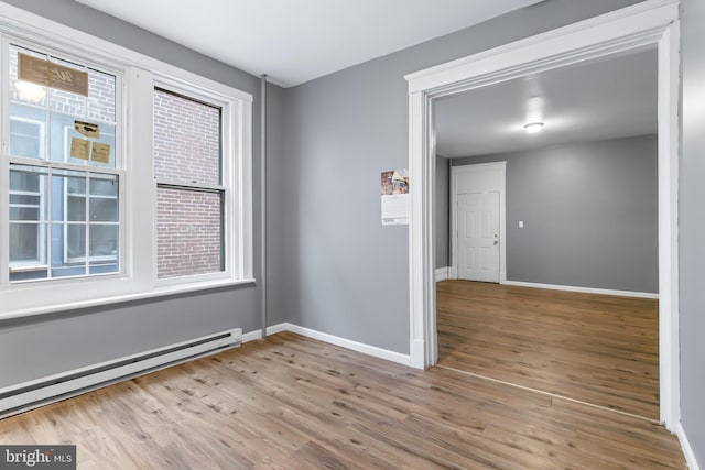 unfurnished room featuring baseboard heating and light hardwood / wood-style flooring