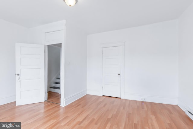 empty room with light hardwood / wood-style flooring and baseboard heating