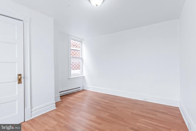 unfurnished room featuring a baseboard heating unit and light wood-type flooring