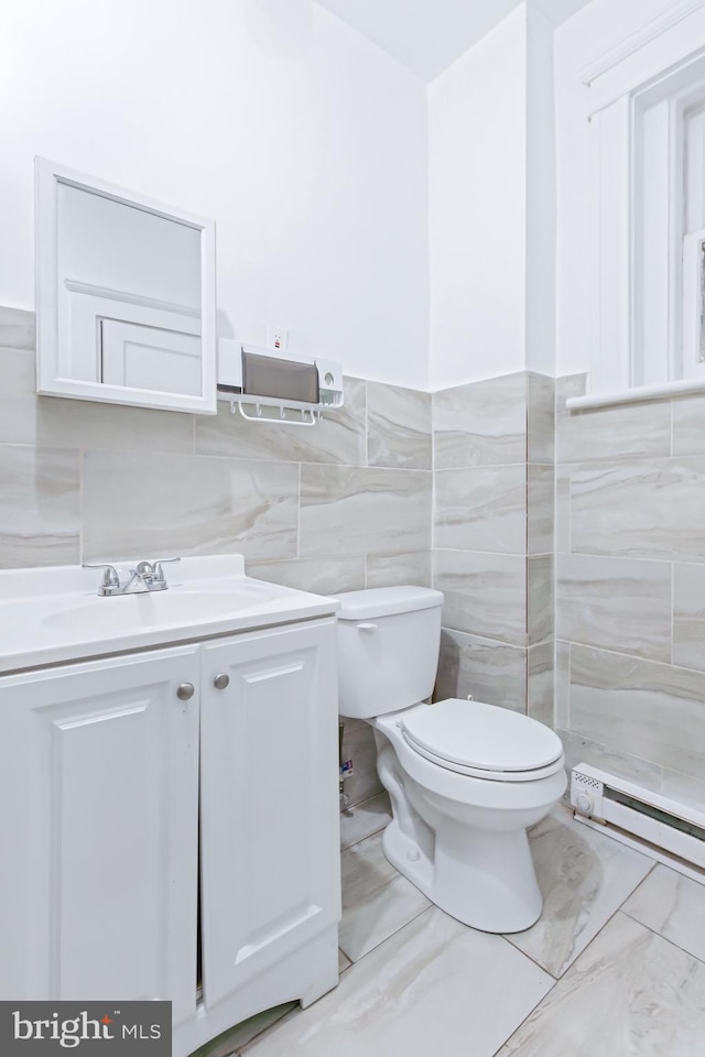 bathroom with vanity, a baseboard heating unit, tile walls, and toilet