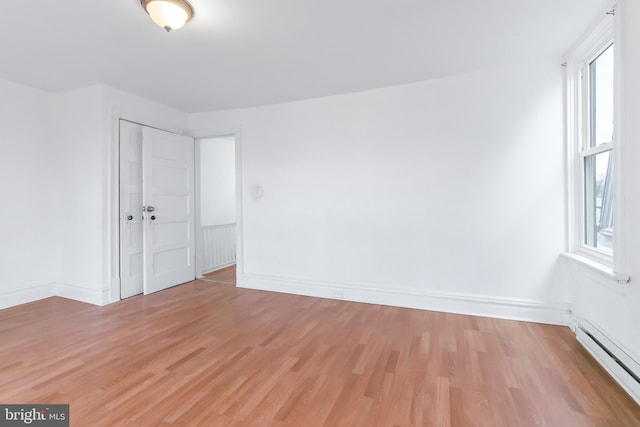 spare room featuring a baseboard radiator and light hardwood / wood-style flooring