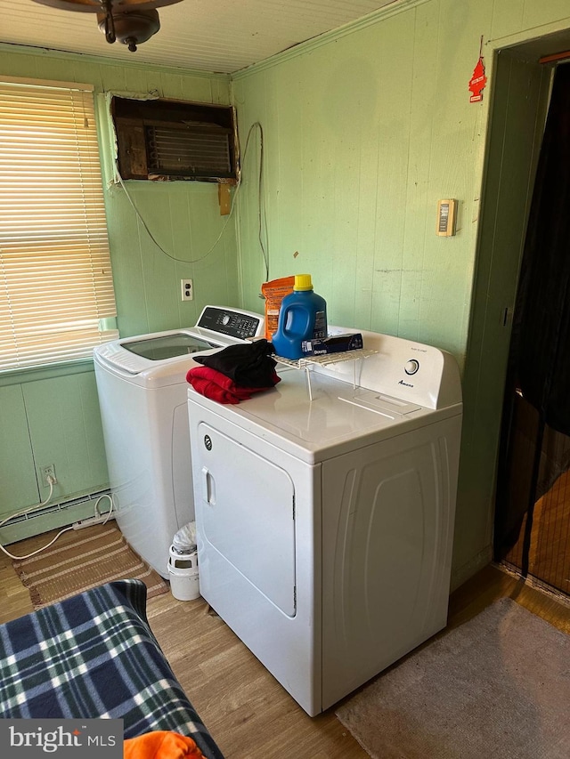 clothes washing area featuring a baseboard radiator, washing machine and clothes dryer, and light hardwood / wood-style floors