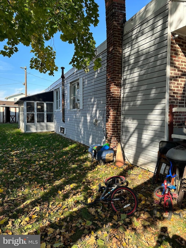 view of side of property featuring a sunroom and a yard