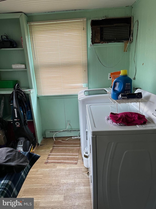 laundry room featuring an AC wall unit, washer and dryer, baseboard heating, and light wood-type flooring