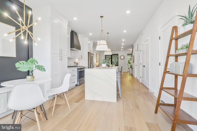 kitchen with a kitchen island, wall chimney exhaust hood, white cabinets, and appliances with stainless steel finishes