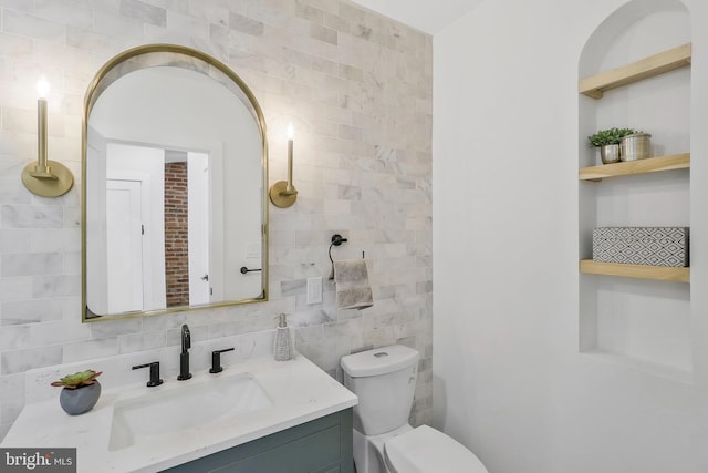 bathroom with vanity, tile walls, and toilet