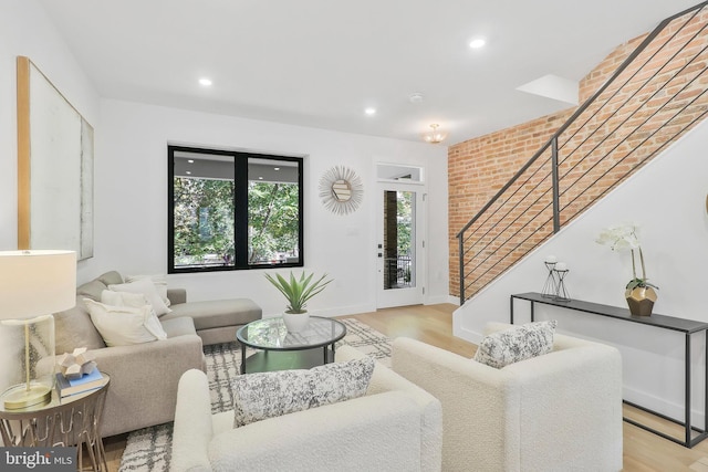 living room featuring brick wall and light hardwood / wood-style flooring