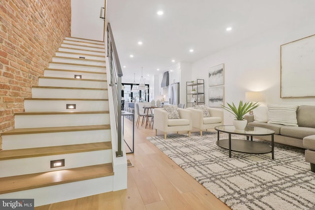 stairs with hardwood / wood-style floors and brick wall