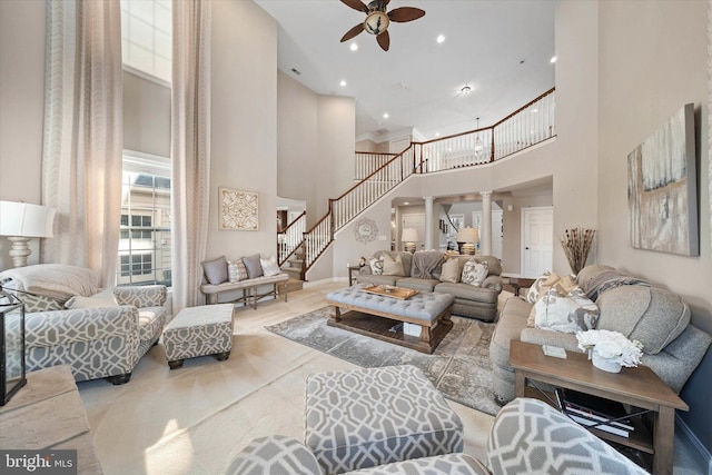 living room with a towering ceiling, light colored carpet, ceiling fan, and ornate columns