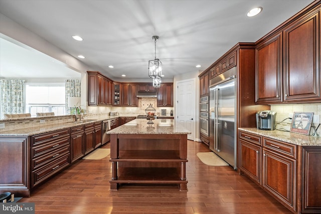 kitchen featuring sink, decorative light fixtures, a center island, dark hardwood / wood-style floors, and stainless steel appliances