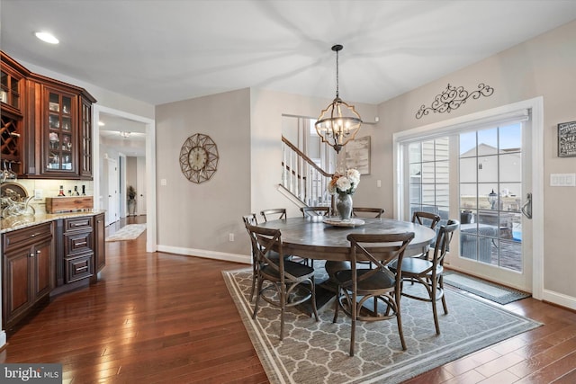 dining room featuring indoor bar, dark hardwood / wood-style floors, and a chandelier