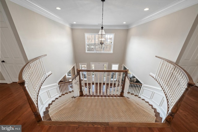 stairway with an inviting chandelier, ornamental molding, hardwood / wood-style floors, and a high ceiling