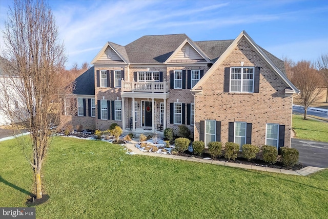 view of front facade featuring a balcony and a front yard