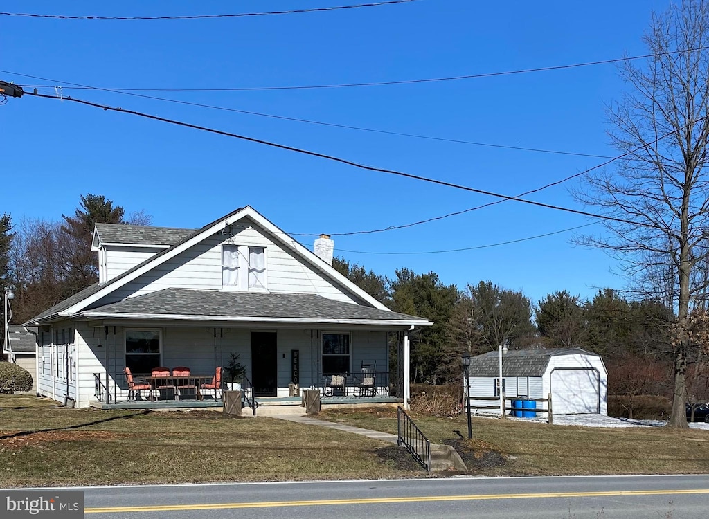 view of front of home with a shed, a front yard, and covered porch