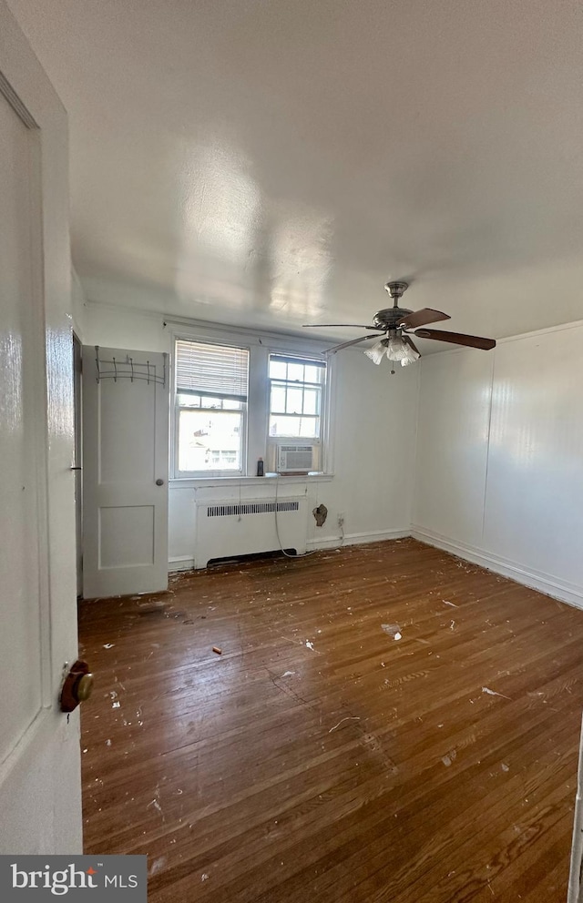 spare room with cooling unit, ceiling fan, radiator heating unit, and dark hardwood / wood-style floors