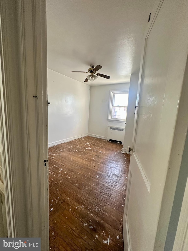 unfurnished room with ceiling fan, dark hardwood / wood-style floors, and radiator