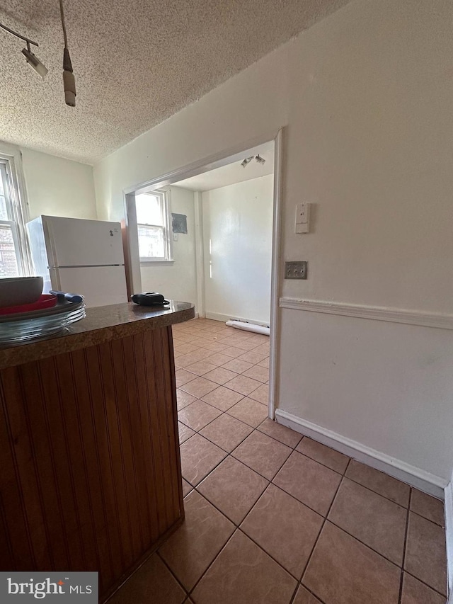 kitchen featuring tile patterned flooring, a baseboard radiator, a textured ceiling, and white fridge