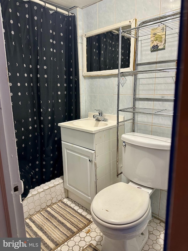 bathroom with vanity, toilet, and tile walls