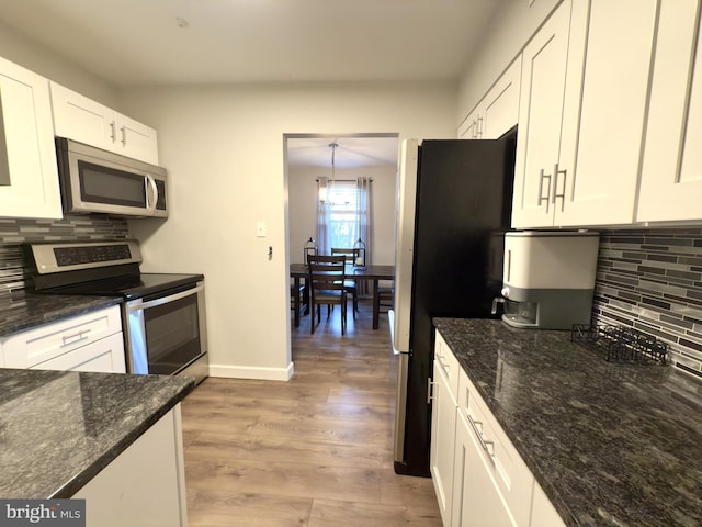 kitchen with white cabinetry, stainless steel appliances, tasteful backsplash, dark stone counters, and light wood-type flooring