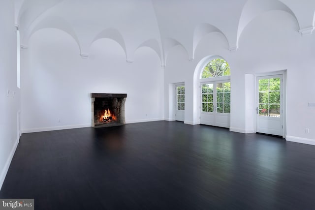 87 Library Pl, Princeton, NJ 08540 - unfurnished living room featuring a lit fireplace, dark wood-style flooring, a towering ceiling, and baseboards