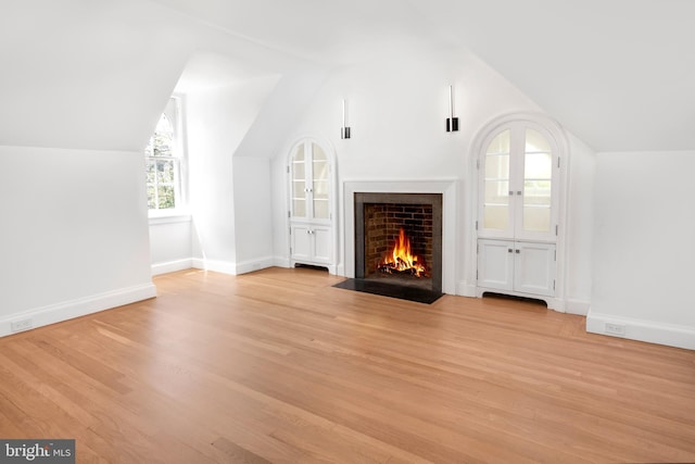 87 Library Pl, Princeton, NJ 08540 - unfurnished living room with vaulted ceiling, light wood-type flooring, a fireplace with flush hearth, and baseboards