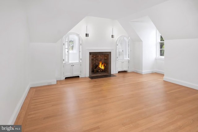 87 Library Pl, Princeton, NJ 08540 - unfurnished living room featuring vaulted ceiling, light wood-style flooring, a fireplace with flush hearth, and baseboards