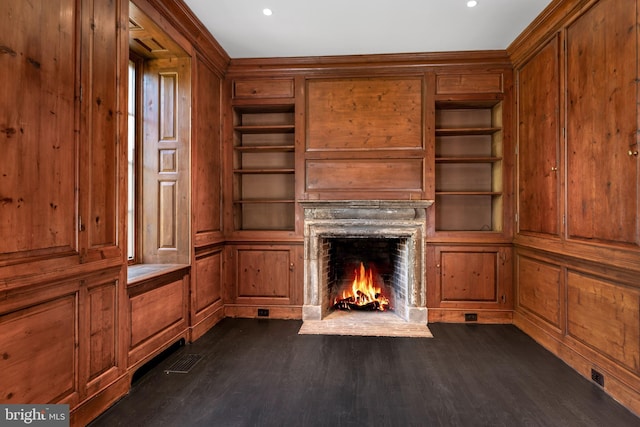 87 Library Pl, Princeton, NJ 08540 - unfurnished living room featuring built in shelves, a fireplace with flush hearth, wood walls, and dark wood-style floors