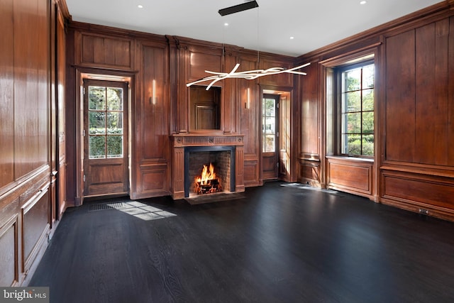 87 Library Pl, Princeton, NJ 08540 - unfurnished living room featuring plenty of natural light, a lit fireplace, wood walls, dark wood-type flooring, and a decorative wall